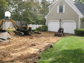 Failing asphalt driveway is removed and replaced with a cobble edged stone driveway.